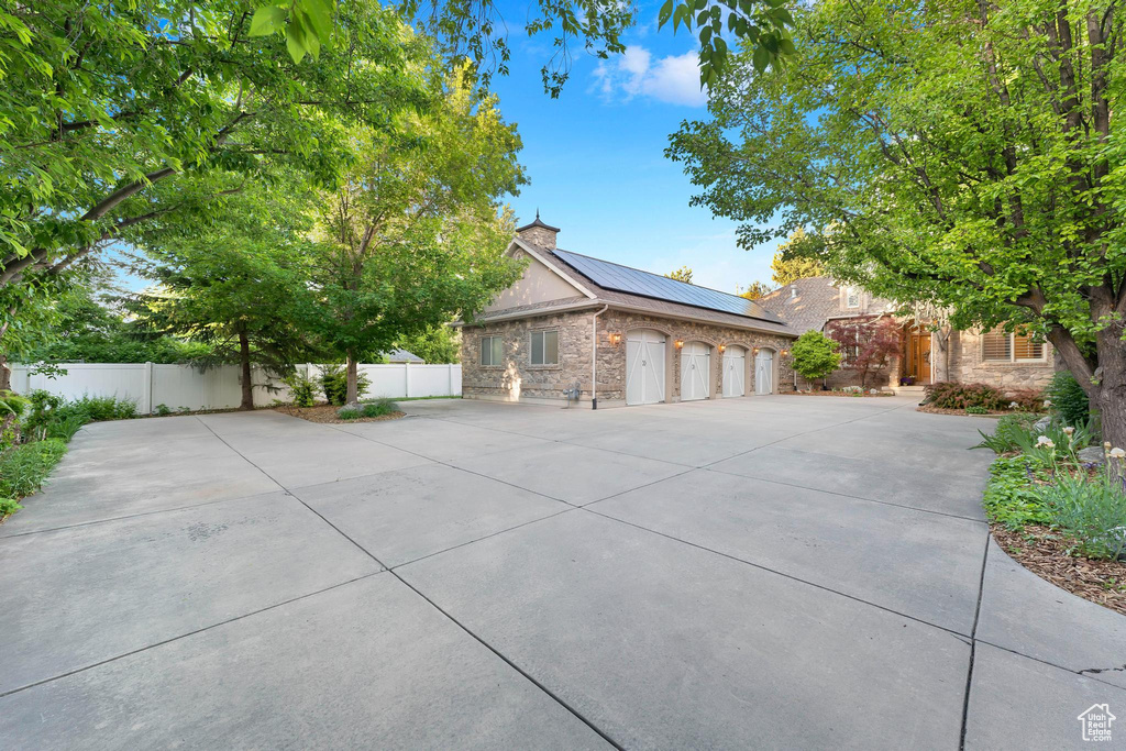 View of front facade with roof mounted solar panels, stone siding, a standing seam roof, and concrete driveway