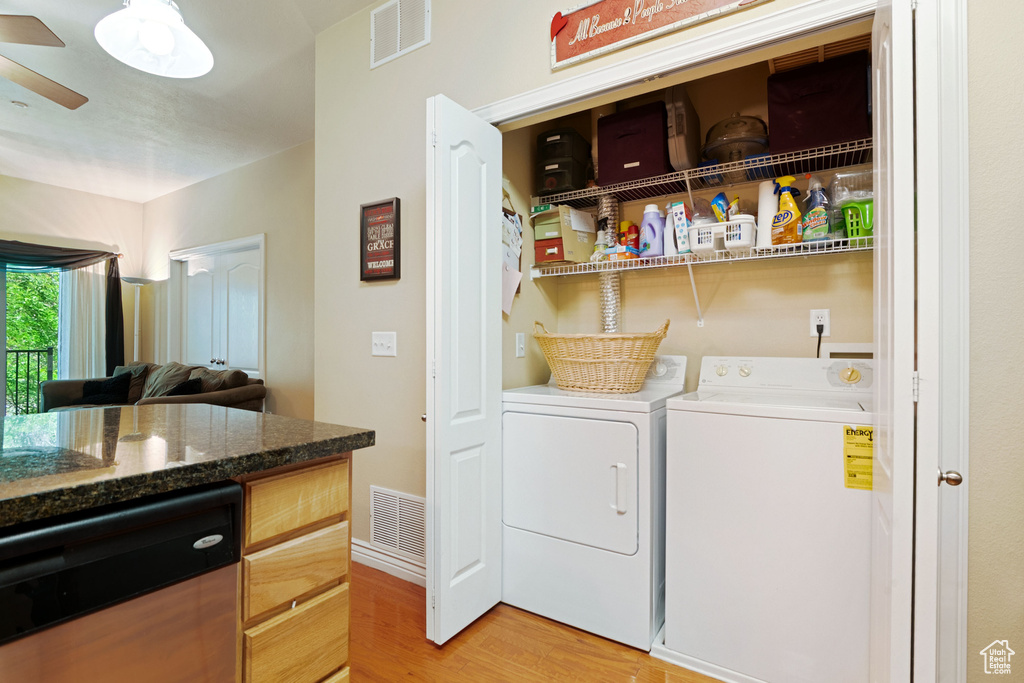 Laundry room featuring independent washer and dryer, light wood-type flooring, and a ceiling fan