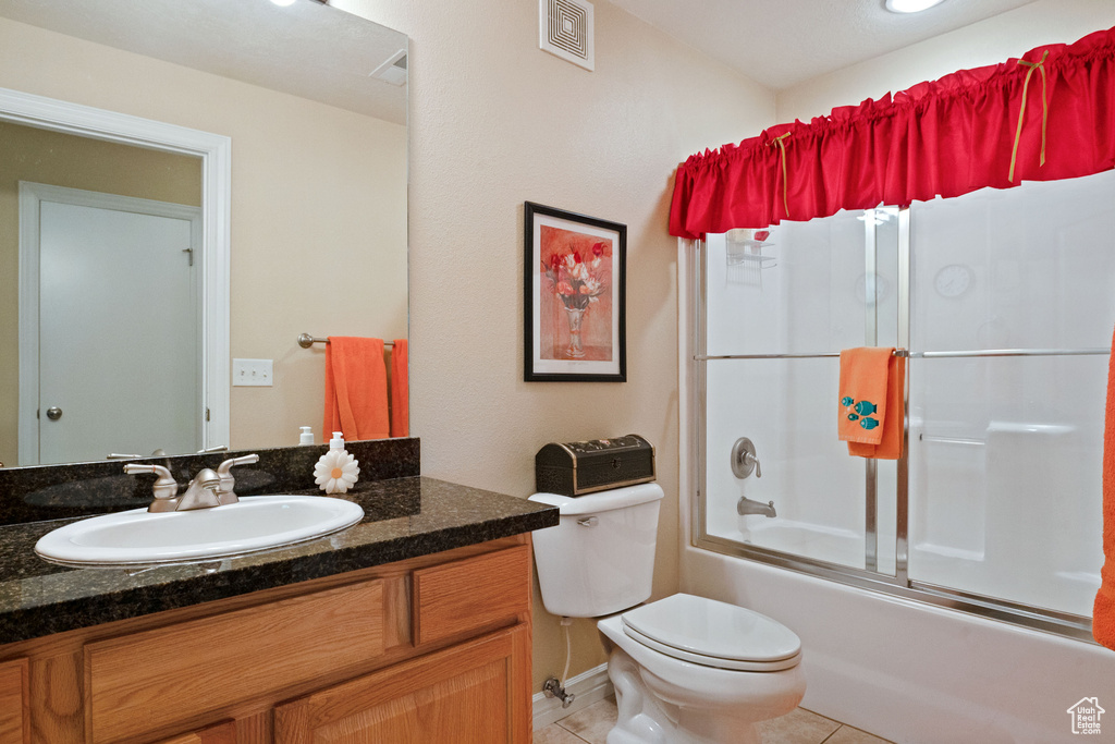 Full bath featuring tile patterned flooring, toilet, vanity, and combined bath / shower with glass door