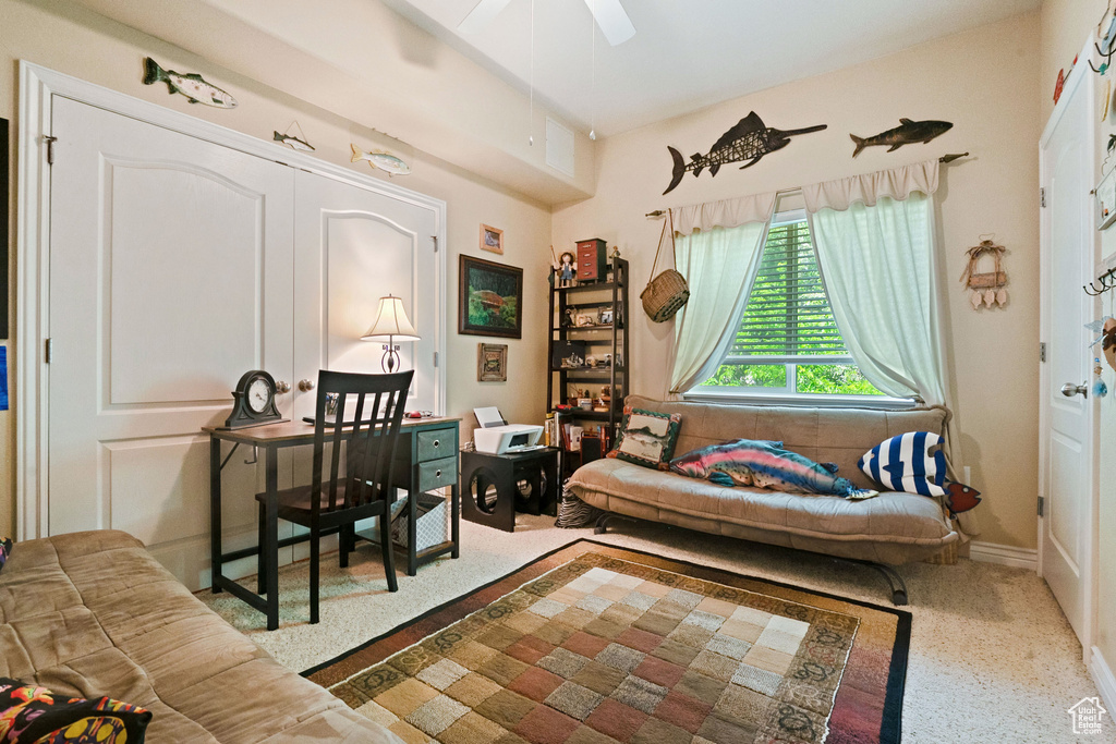 Carpeted living room with ceiling fan and baseboards