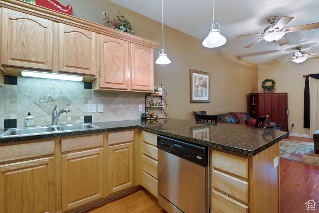 Kitchen with dishwasher, a peninsula, a sink, decorative backsplash, and light wood-style flooring
