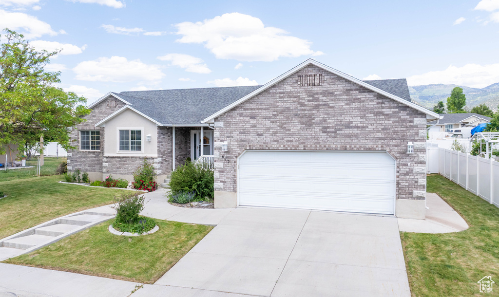 Ranch-style house with an attached garage, concrete driveway, brick siding, and a mountain view