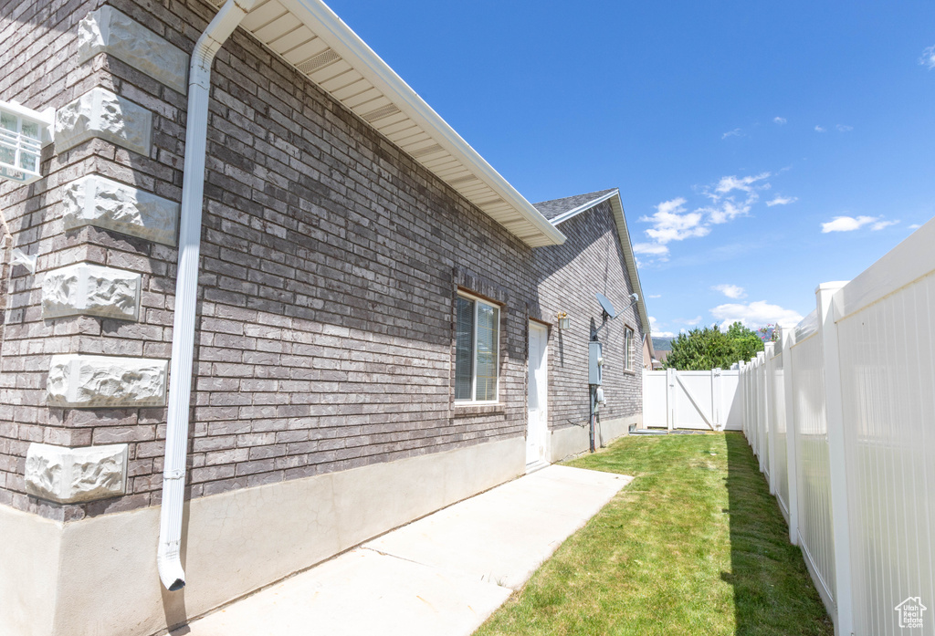 View of property exterior featuring brick siding, a patio, and a gate