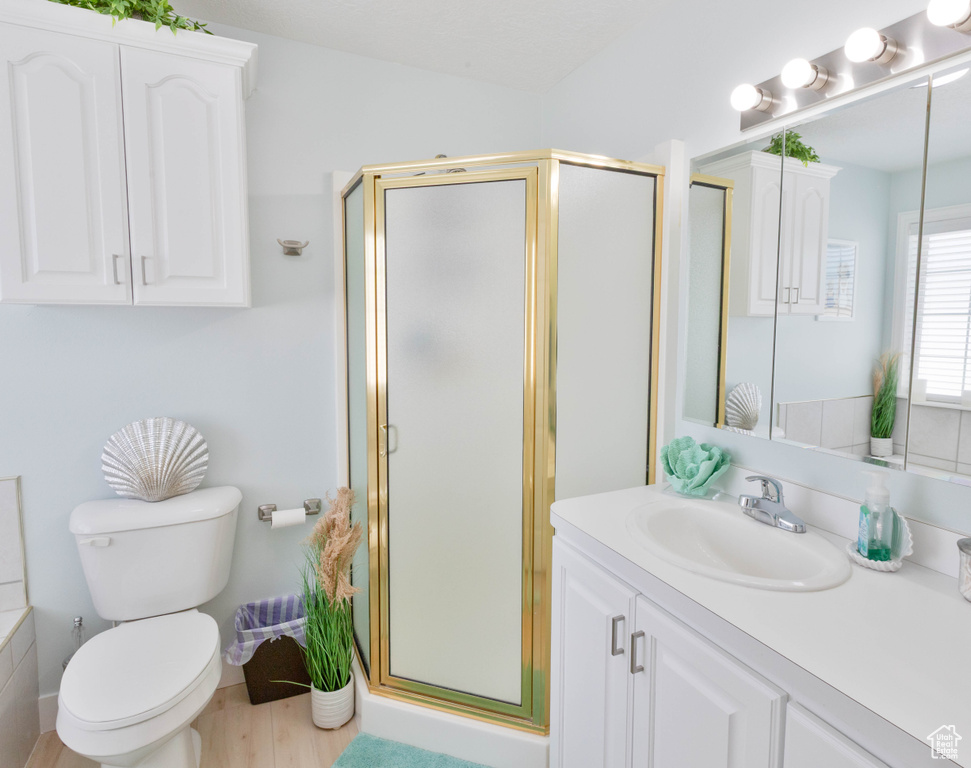 Full bath with vanity, a shower stall, toilet, and wood finished floors