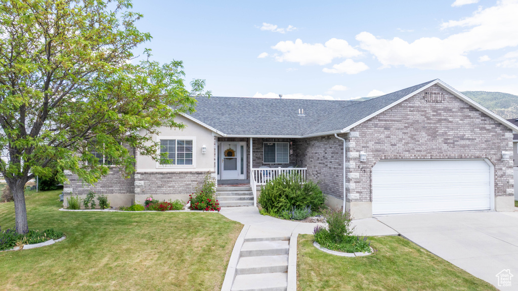 Single story home with a garage, a porch, concrete driveway, a front lawn, and brick siding