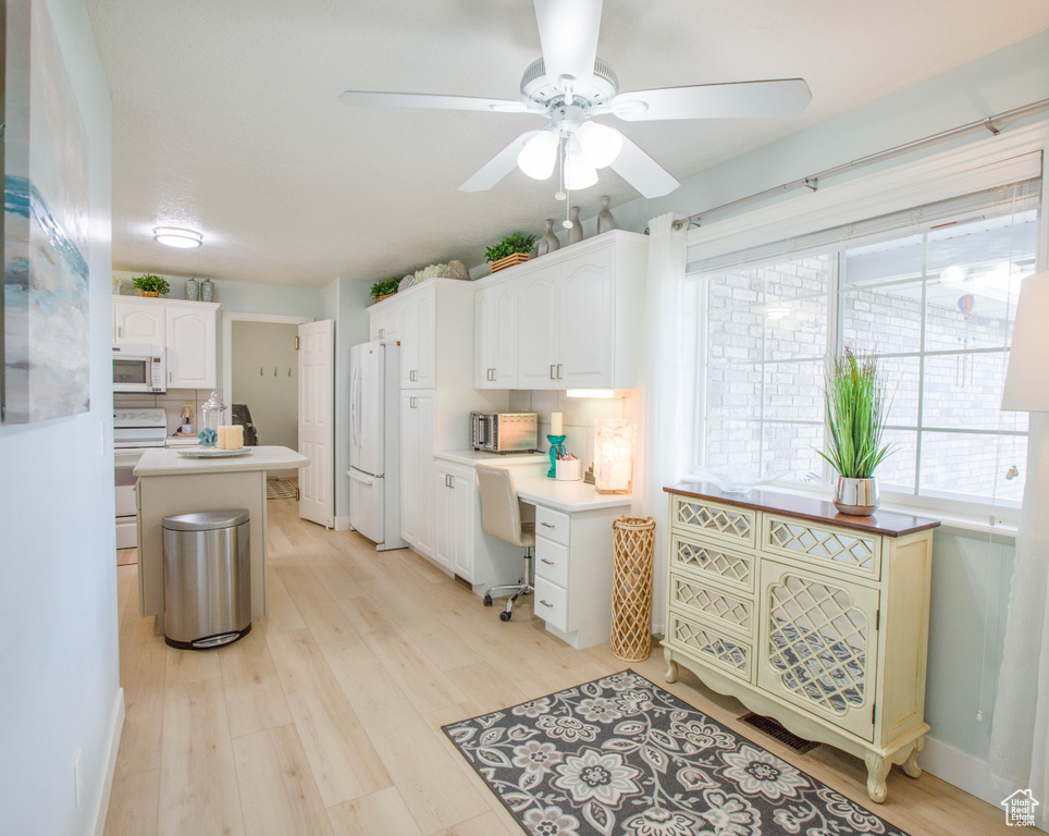 Kitchen with white appliances, ceiling fan, light wood-style flooring, white cabinetry, and light countertops