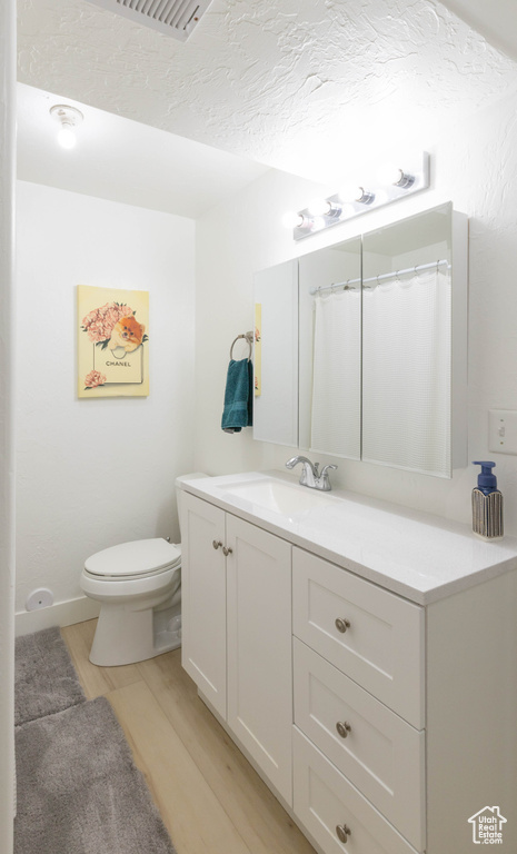 Full bathroom with wood finished floors, vanity, and toilet