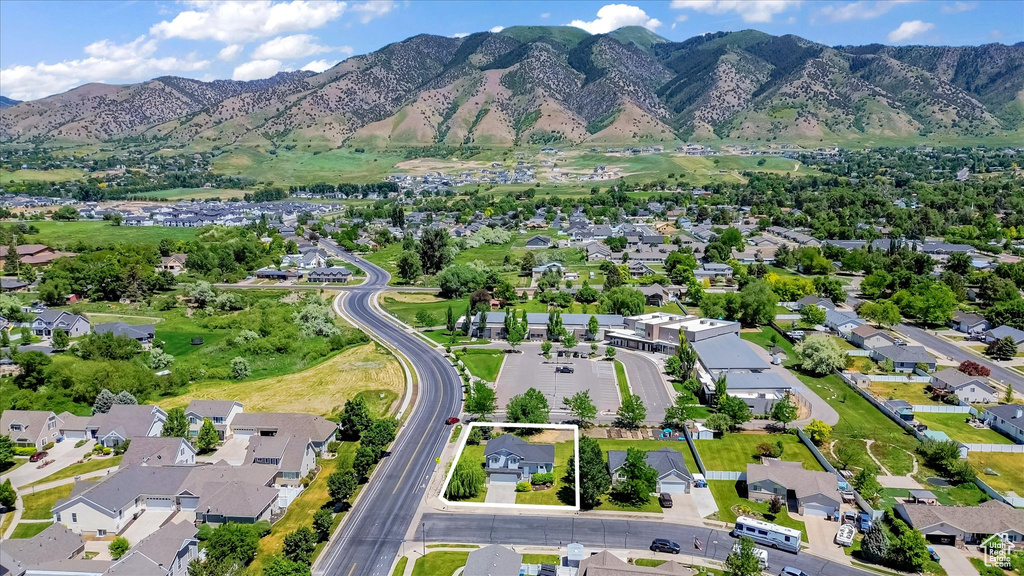 Aerial view of property and surrounding area featuring nearby suburban area and a mountainous background