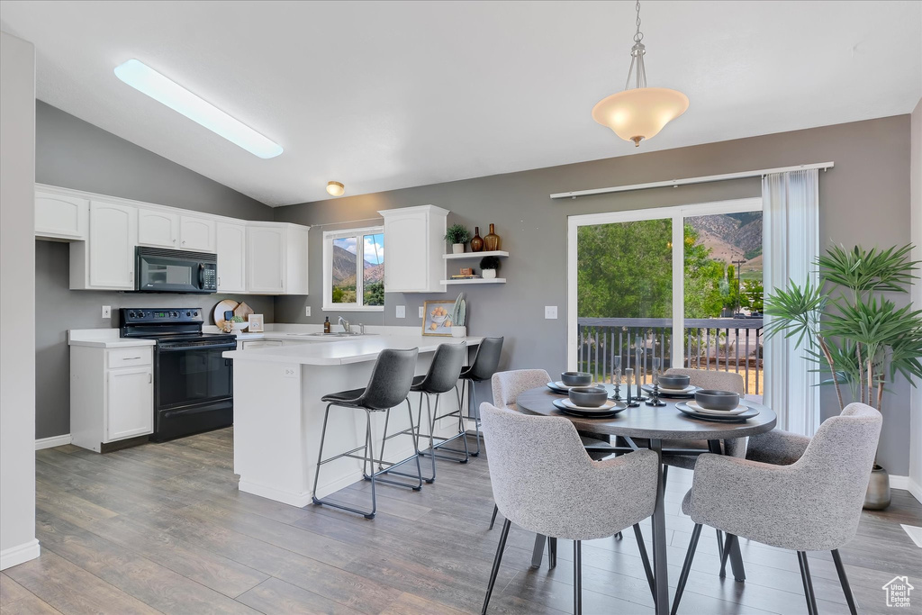 Kitchen with black appliances, a sink, lofted ceiling, light countertops, and white cabinetry