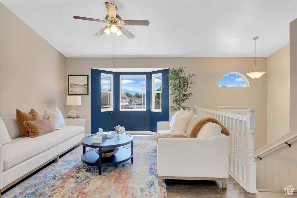 Living room with healthy amount of natural light, a ceiling fan, wood finished floors, and baseboards