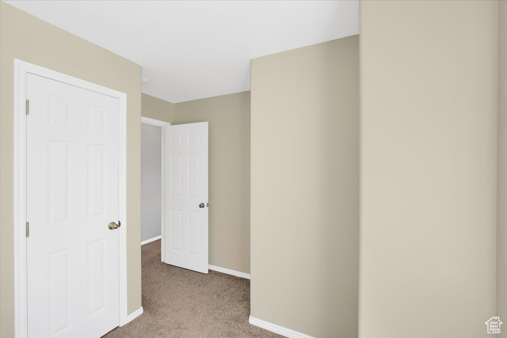 Unfurnished bedroom featuring light carpet and baseboards
