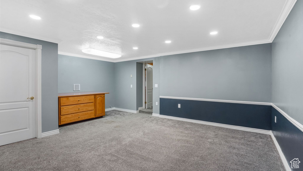 Basement with light colored carpet, recessed lighting, crown molding, and baseboards