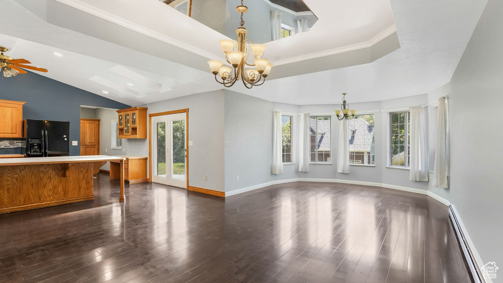 Unfurnished living room featuring a baseboard radiator, a chandelier, plenty of natural light, and lofted ceiling
