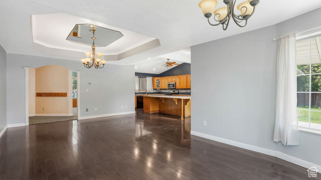 Kitchen with a chandelier, stainless steel microwave, a raised ceiling, a kitchen bar, and baseboards