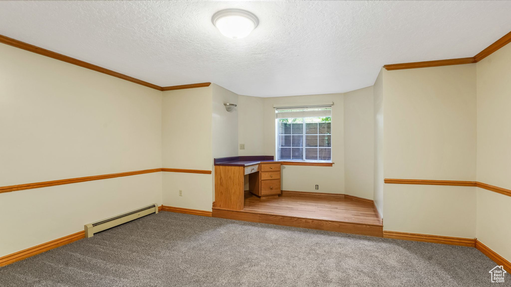 Unfurnished living room with baseboard heating, ornamental molding, light carpet, baseboards, and a textured ceiling