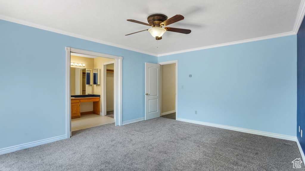 Unfurnished bedroom with crown molding, carpet floors, baseboards, ensuite bath, and ceiling fan