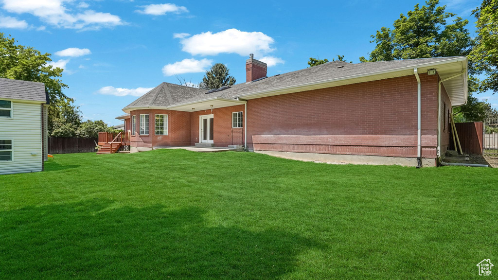 Back of property with a chimney, brick siding, a patio, and roof with shingles
