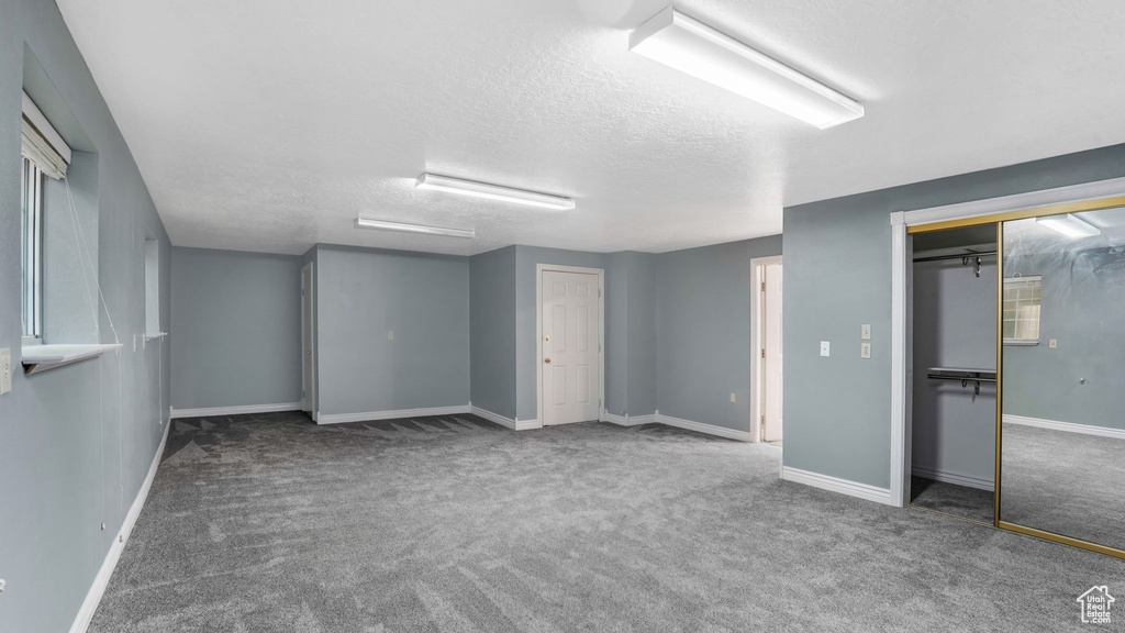 Basement with carpet floors, a textured ceiling, and baseboards