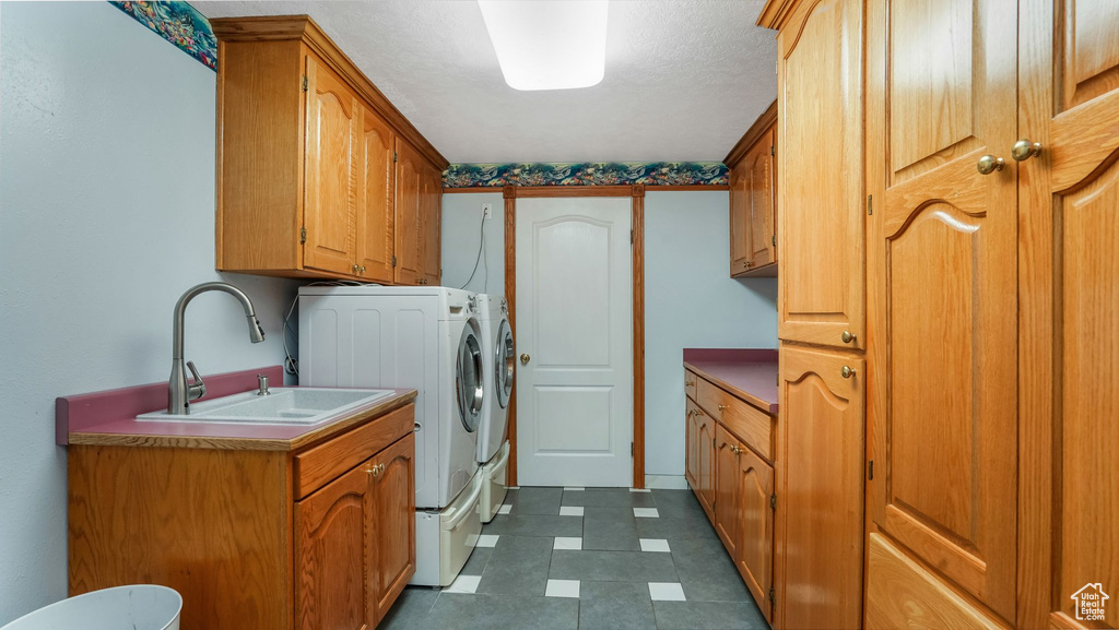 Washroom with independent washer and dryer, cabinet space, and dark tile patterned floors