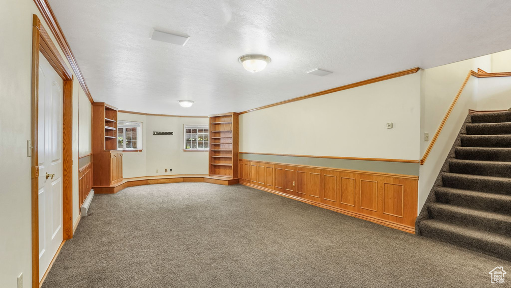 Spare room featuring carpet floors, stairs, ornamental molding, and built in shelves
