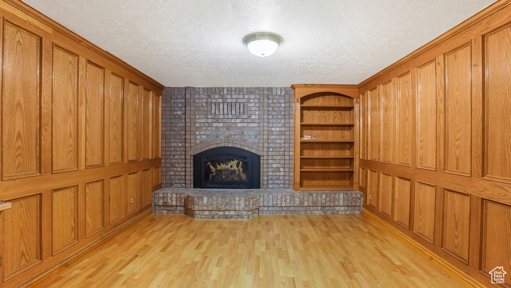 Unfurnished living room featuring a textured ceiling, light wood-type flooring, and a fireplace