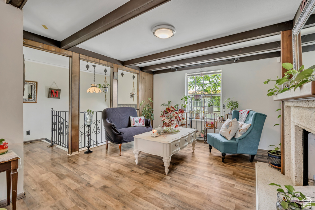 Living area with beam ceiling, light wood-style flooring, and a premium fireplace