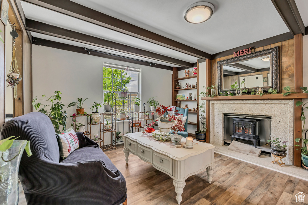 Living room with wood finished floors, beamed ceiling, and a wood stove