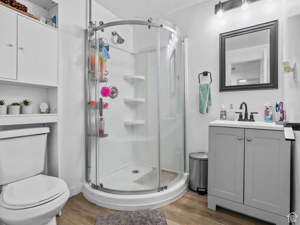Full bathroom with wood finished floors, a stall shower, and a textured ceiling