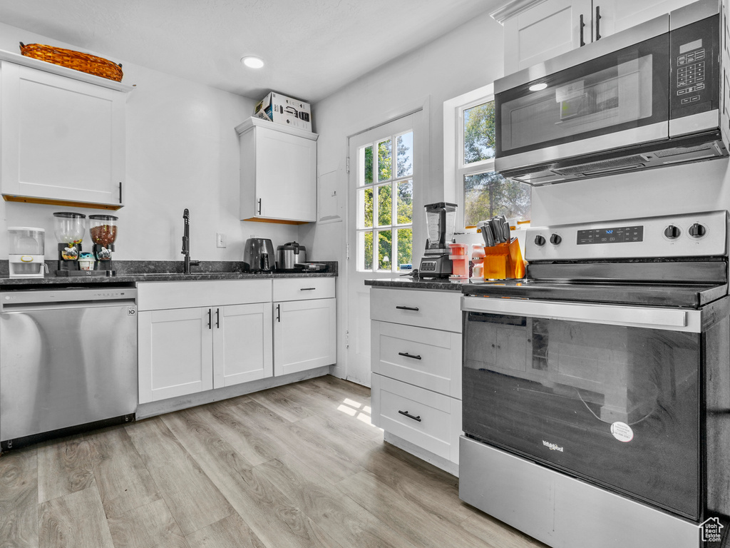 Kitchen featuring stainless steel appliances, light wood-type flooring, white cabinetry, a sink, and recessed lighting