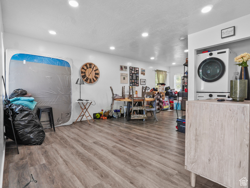Misc room featuring stacked washer / dryer, recessed lighting, wood finished floors, and a textured ceiling