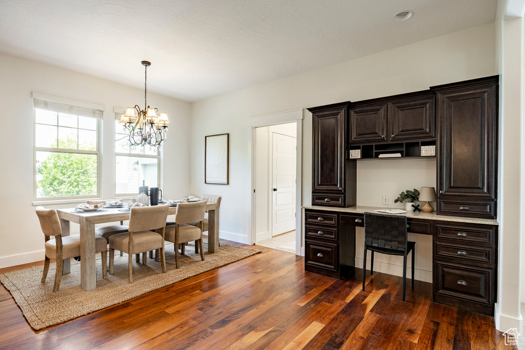 Dining area featuring dark wood-style flooring, baseboards, built in study area, and a chandelier