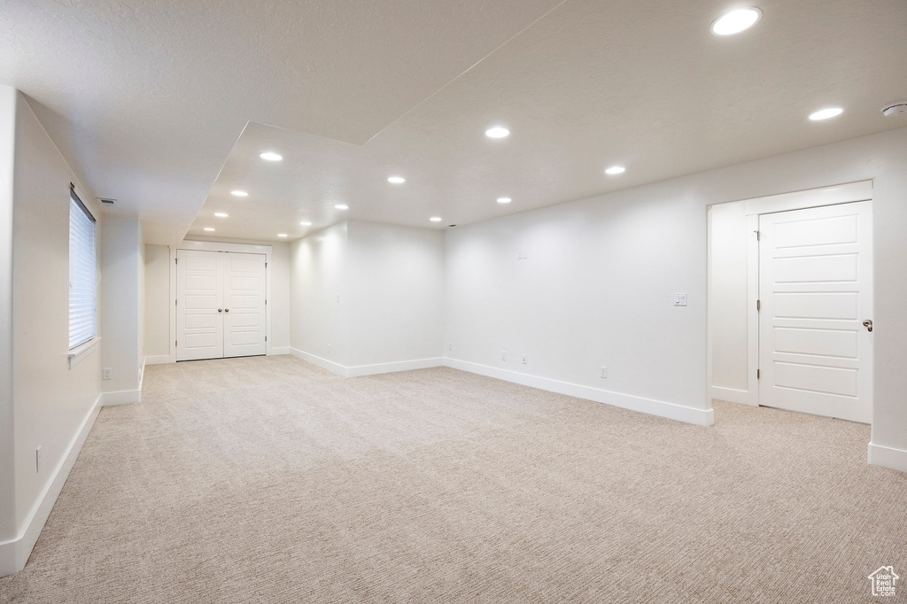 Spare room featuring light colored carpet, recessed lighting, baseboards, and a smoke detector