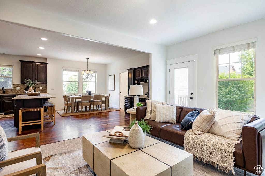 Living area with dark wood-style flooring, recessed lighting, and a chandelier
