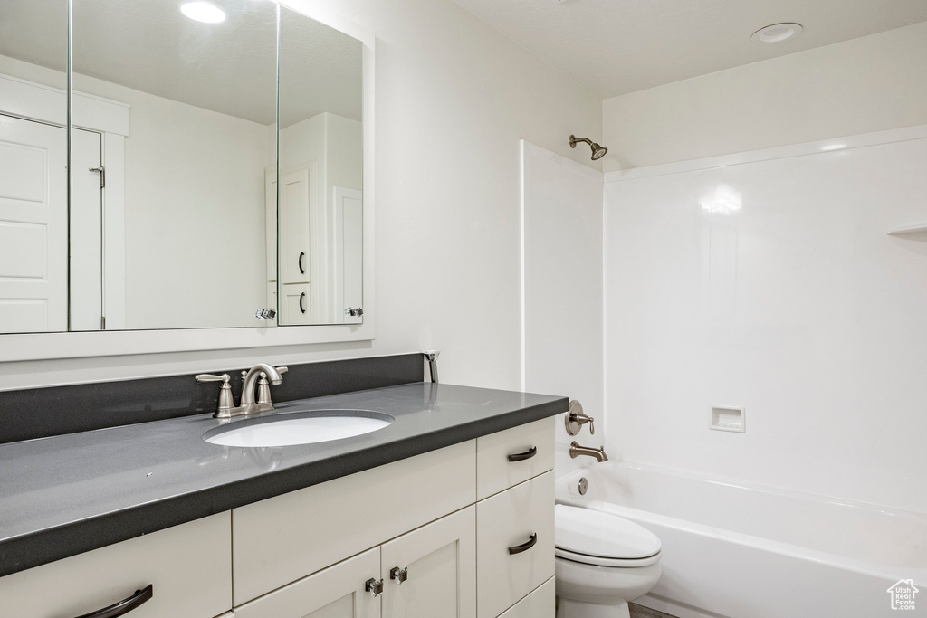 Full bathroom with vanity, toilet, tub / shower combination, and recessed lighting