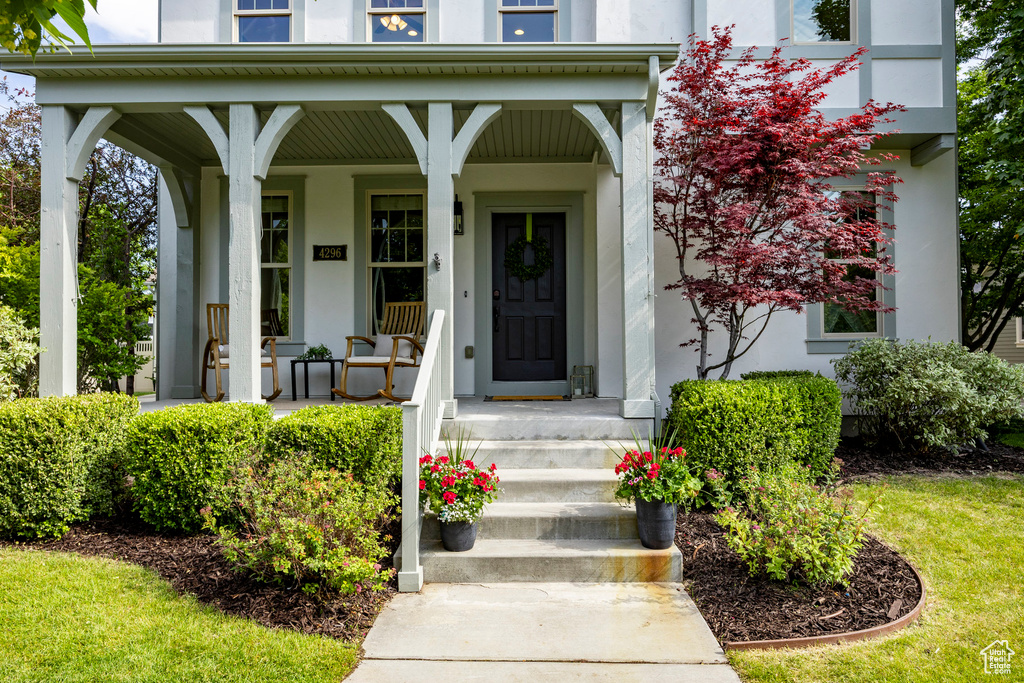 View of exterior entry with stucco siding and a porch