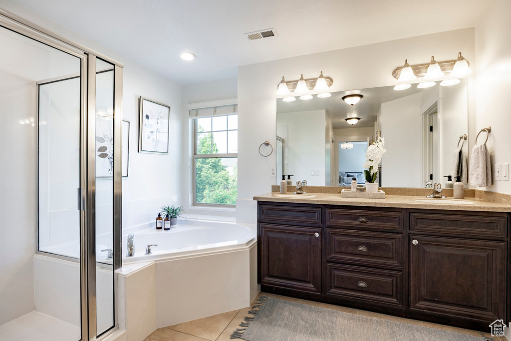 Bathroom featuring double vanity, a stall shower, a garden tub, and tile patterned floors