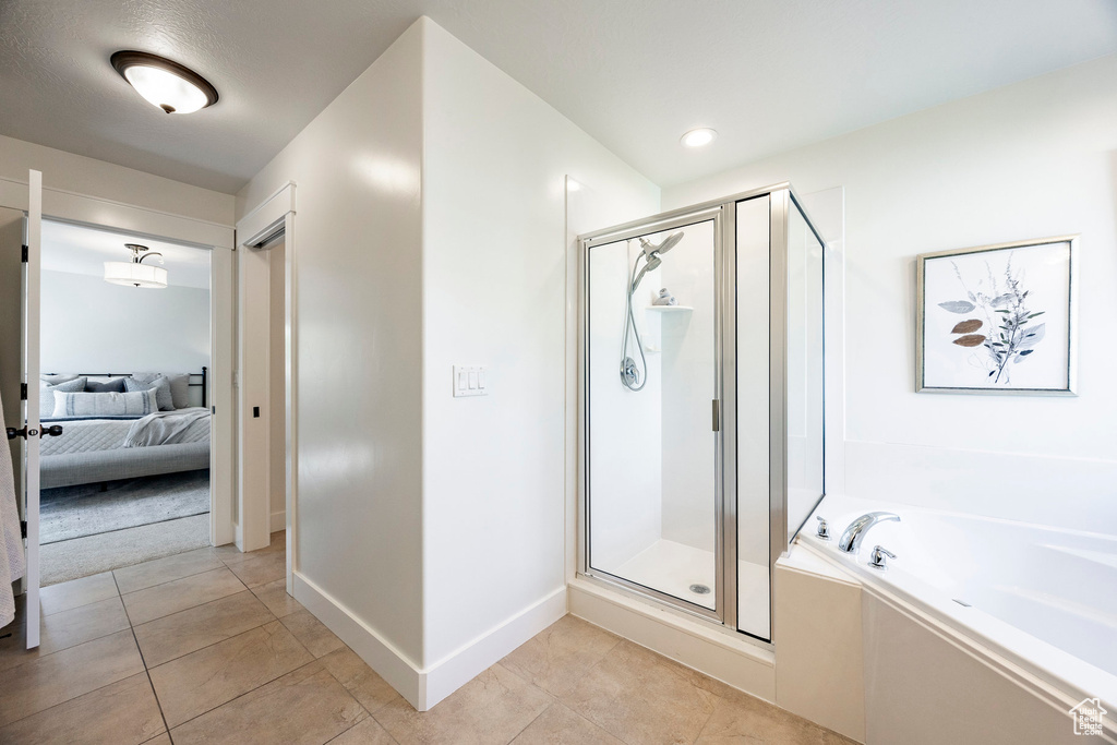 Ensuite bathroom featuring a garden tub, a stall shower, tile patterned flooring, and baseboards