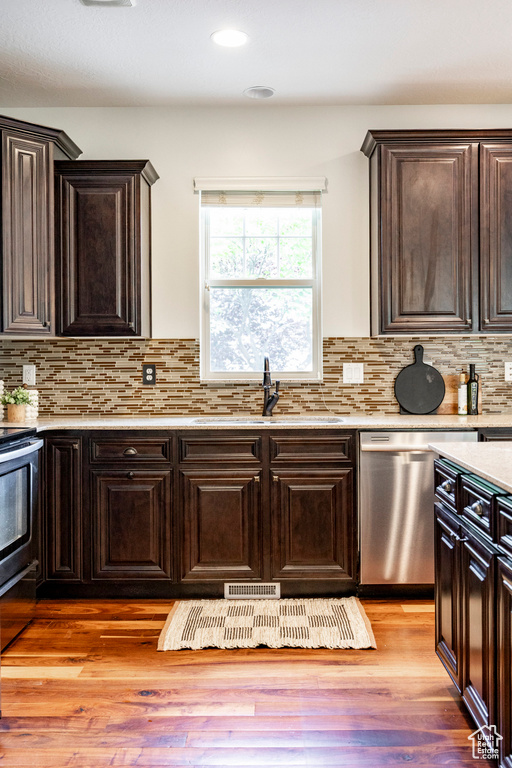 Kitchen featuring stainless steel dishwasher, a sink, range, dark brown cabinetry, and recessed lighting
