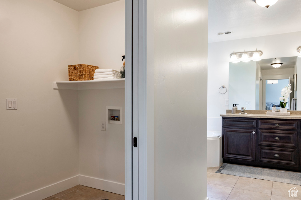 Full bath featuring a garden tub, vanity, tile patterned floors, and baseboards