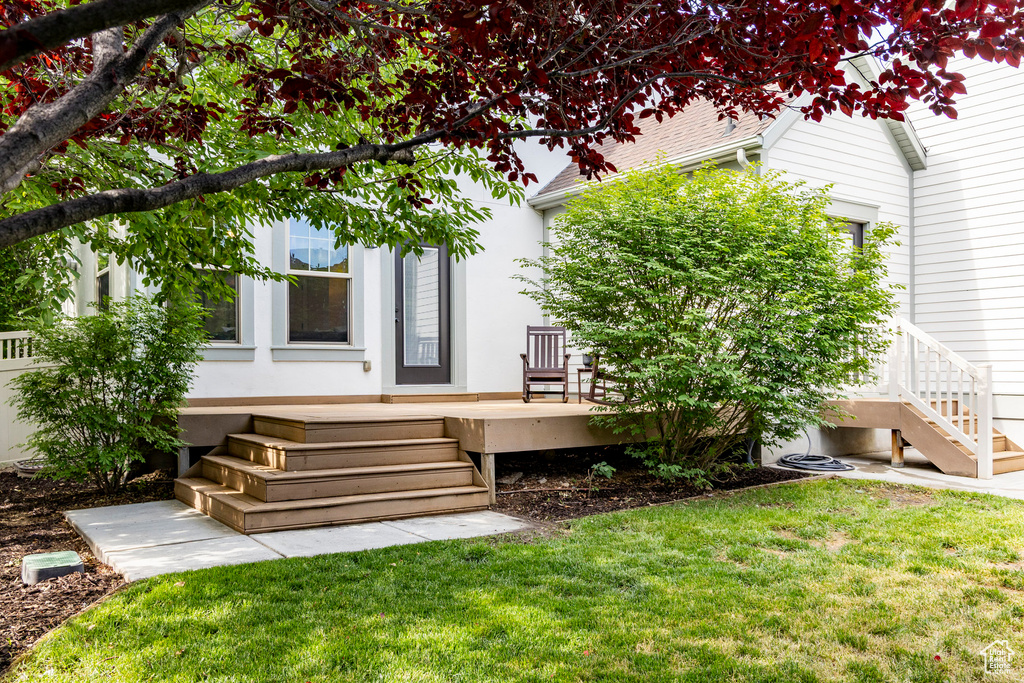 Back of property featuring a deck, a yard, and stucco siding