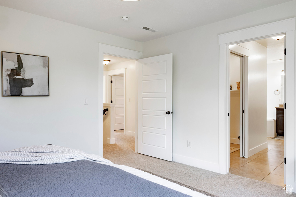 Unfurnished bedroom with light colored carpet, baseboards, and light tile patterned floors