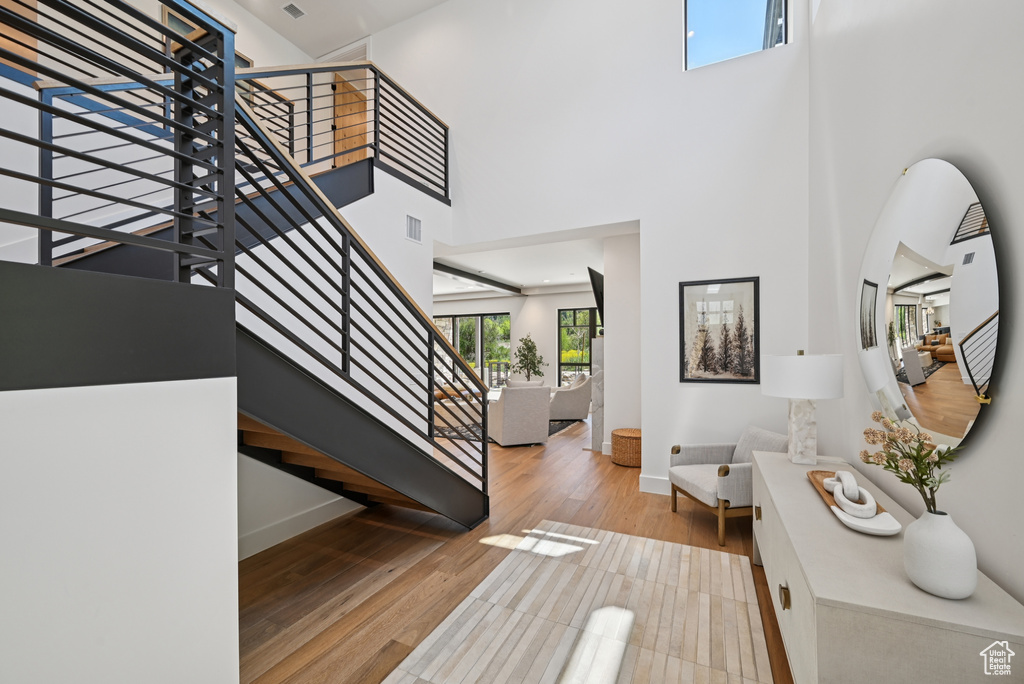 Stairway featuring baseboards, wood finished floors, and a high ceiling