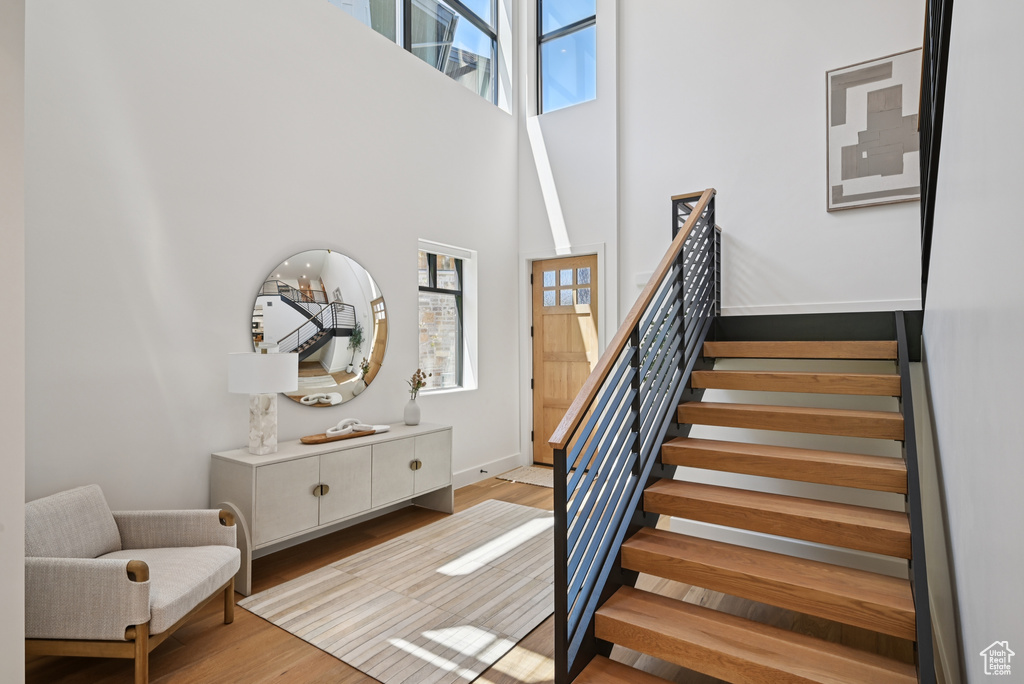 Stairway featuring a towering ceiling, healthy amount of natural light, wood finished floors, and baseboards