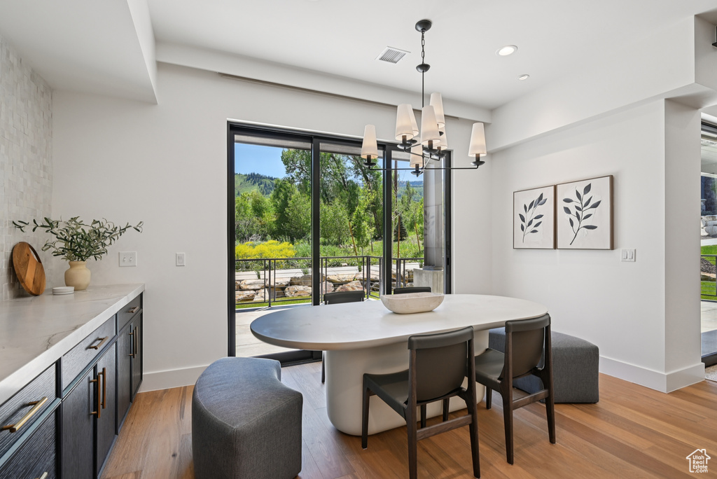 Dining space with a chandelier, baseboards, light wood-style flooring, and recessed lighting
