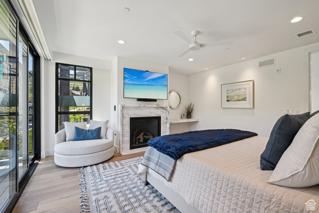 Bedroom featuring wood finished floors, multiple windows, recessed lighting, a fireplace, and a ceiling fan