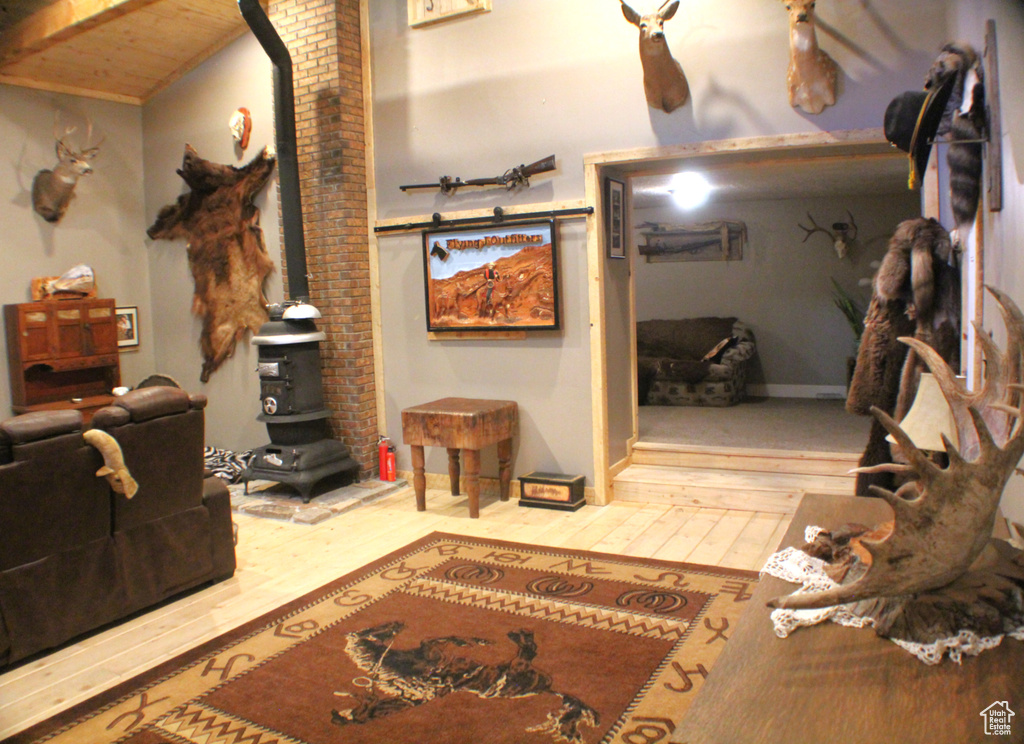 Living room with a wood stove, hardwood / wood-style floors, and wooden ceiling