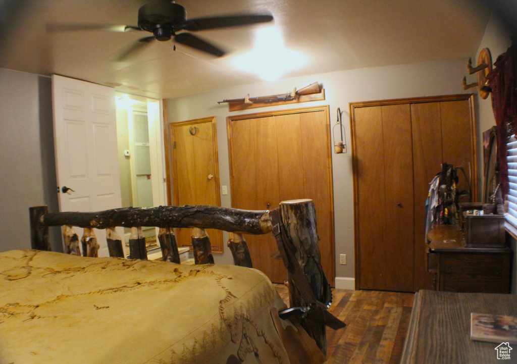 Bedroom with wood finished floors, two closets, baseboards, and a ceiling fan