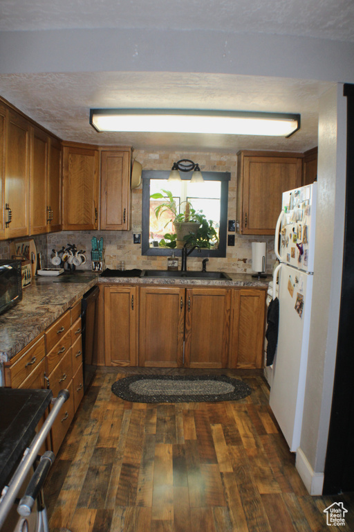 Kitchen with a sink, brown cabinetry, and dark wood-style flooring