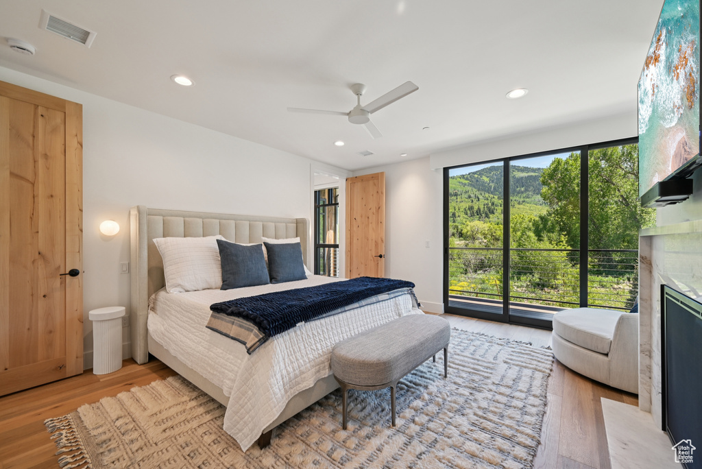 Bedroom featuring light wood-style flooring, access to outside, a fireplace, a ceiling fan, and recessed lighting