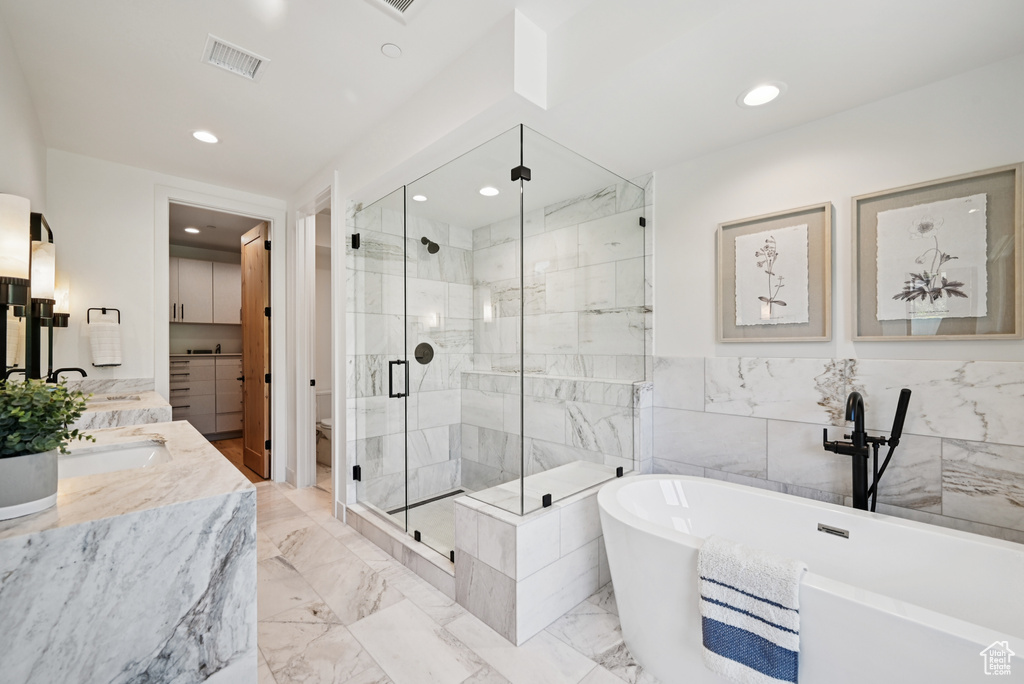 Full bathroom featuring a stall shower, vanity, a freestanding bath, recessed lighting, and marble tiled floors